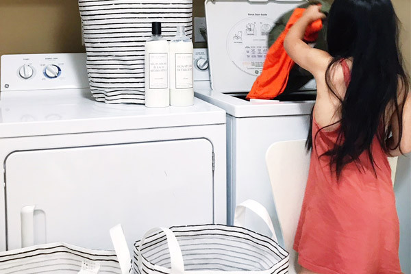 girl putting clothes in washing machine