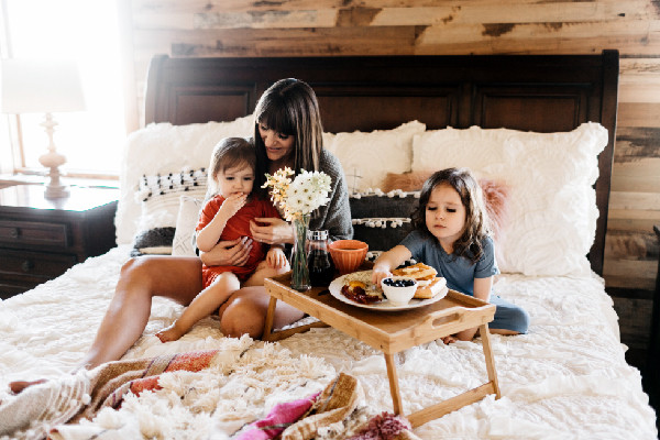 mom with kids in bed eating breakfast
