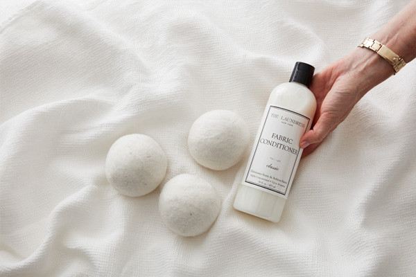 hand with fabric conditioner and dryer balls